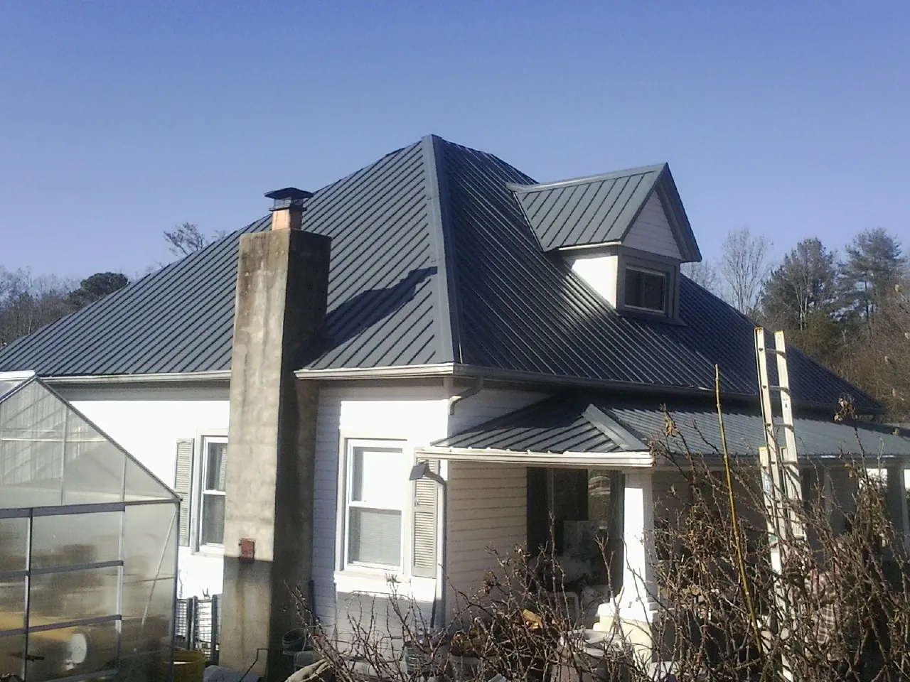 Dark blue standing seam metal roof on a white farmhouse with dormer — Slate & Tile Roof Repair by Roofing Brothers in Banning