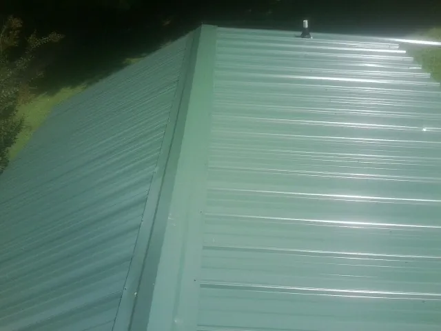 New green metal panels meeting at the ridge of a roof — Flat Roof Repair work by our crew in Banning