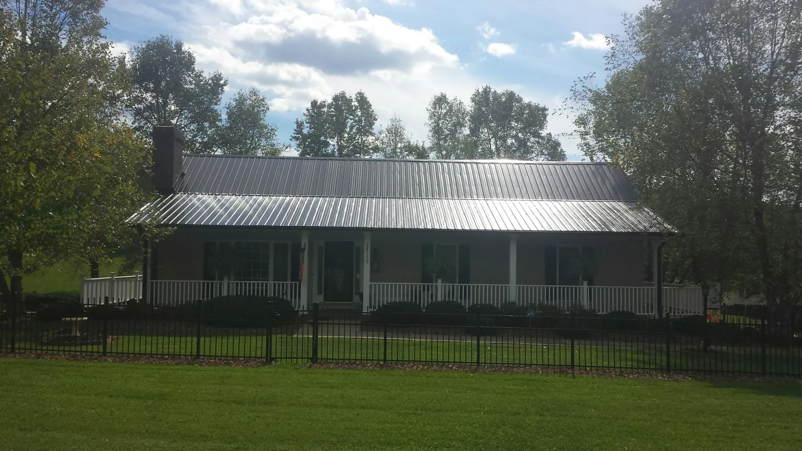 Gray metal roof on a brick ranch with a full width front porch — Gutter Guard Installation work by our crew in Banning