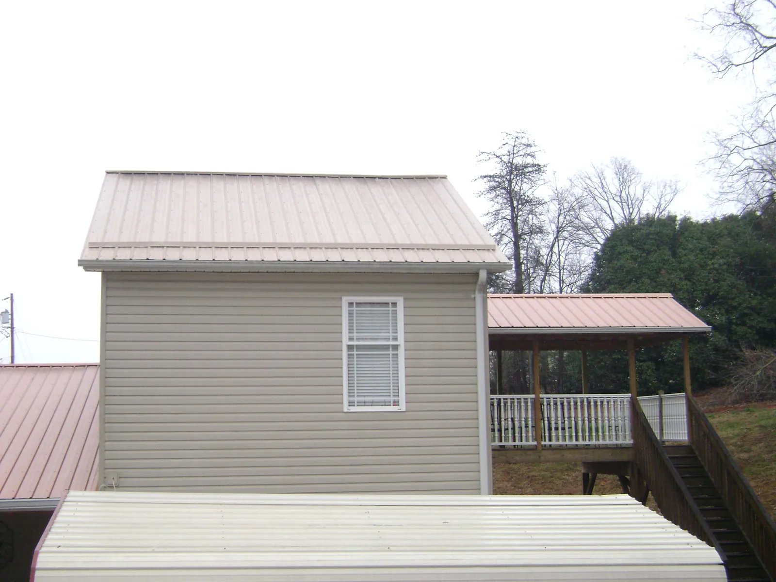 Tan metal roofs on a two story addition and attached porch, from a Roof Replacement job in Banning