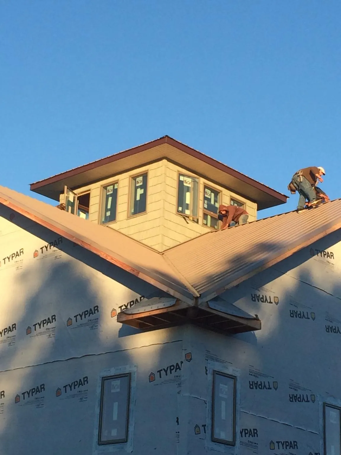 Roofers working around a rooftop cupola on a new metal roof at sunset — Roof Waterproofing in Banning by Roofing Brothers